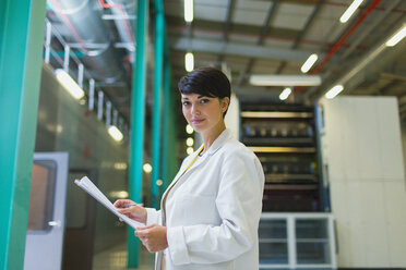 Portrait confident scientist with paperwork in factory - CAIF09037