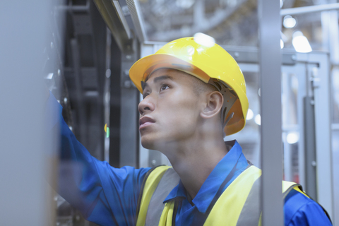 Arbeiter mit Schutzhelm bei der Prüfung von Maschinen in einer Fabrik, lizenzfreies Stockfoto