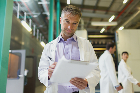 Porträt eines selbstbewussten Wissenschaftlers mit Klemmbrett in einer Fabrik, lizenzfreies Stockfoto