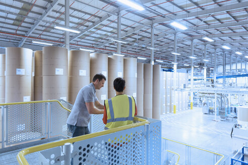 Workers talking on platform above factory - CAIF09078