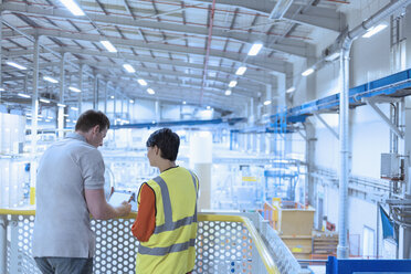 Arbeiter mit digitalem Tablet auf der Plattform über der Fabrik - CAIF09087