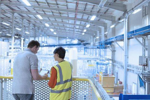 Workers with digital tablet on platform above factory - CAIF09087