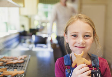 Porträt lächelnd Mädchen essen Lebkuchen Cookie - CAIF09098