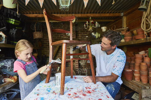Vater und Tochter bemalen einen Stuhl in der Werkstatt - CAIF09099