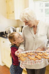 Enkelin umarmt Großmutter beim Lebkuchenbacken - CAIF09107