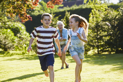 Bruder und Schwester laufen im sonnigen Garten, lizenzfreies Stockfoto