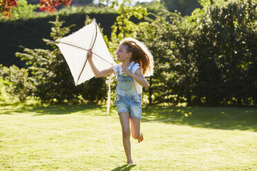 Girl running with kite in sunny garden - CAIF09118