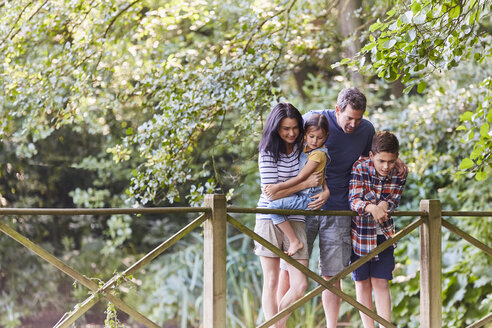 Familie steht auf einem Steg in einem Park mit Bäumen - CAIF09157