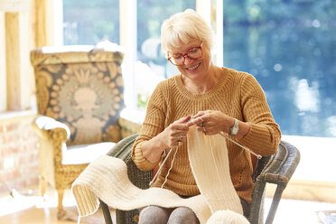 Senior woman knitting in living room - CAIF09167