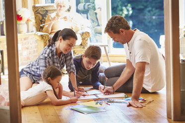 Family drawing and coloring on floor in living room - CAIF09186