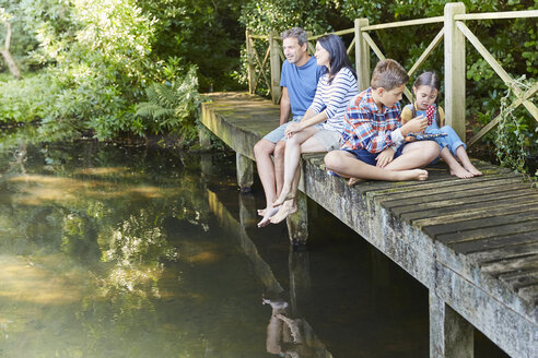 Familie entspannt sich auf dem Steg über den Teich - CAIF09193