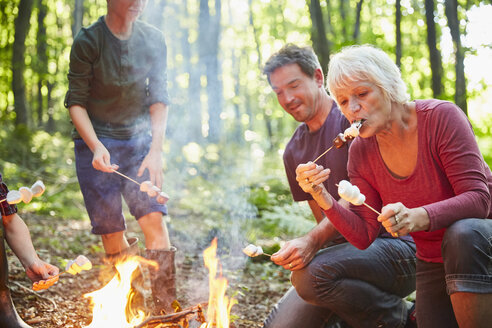 Mehrgenerationenfamilie röstet Marshmallows am Lagerfeuer im Wald - CAIF09195