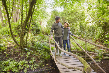 Father and son crossing footbridge in forest - CAIF09197