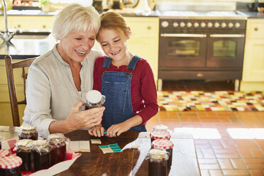 Grandmother and granddaughter canning jam in kitchen - CAIF09200