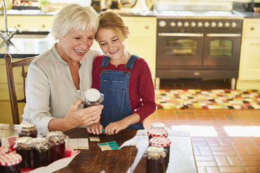 Großmutter und Enkelin beim Einmachen von Marmelade in der Küche - CAIF09200