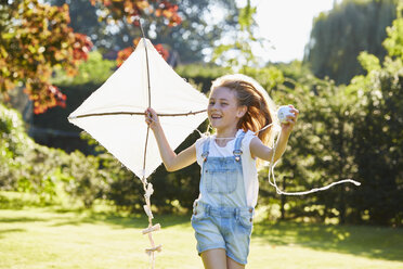 Enthusiastic girl running with kite in sunny garden - CAIF09213