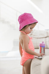 Kleines Mädchen im Badeanzug mit digitalem Tablet auf dem Sofa - CAIF09220
