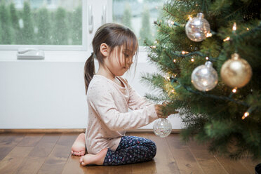 Mädchen im Kleinkindalter schmückt den Weihnachtsbaum - CAIF09222