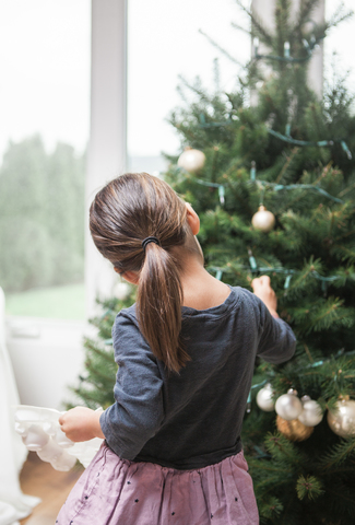 Mädchen im Kleinkindalter schmückt den Weihnachtsbaum, lizenzfreies Stockfoto
