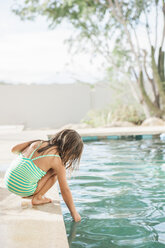 Mädchen im Kleinkindalter testet das Wasser am Rande des Schwimmbeckens - CAIF09227