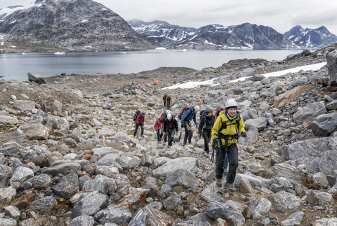 Grönland, Sermersooq, Kulusuk, Schweizerland Alpen, Gruppe von Menschen, die auf Felsen gehen, lizenzfreies Stockfoto