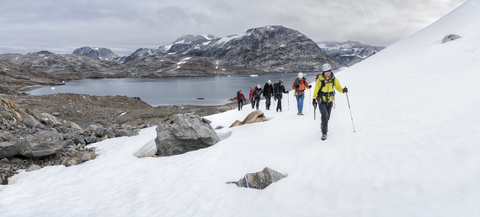 Grönland, Sermersooq, Kulusuk, Schweizerland Alpen, Gruppe von Menschen zu Fuß im Schnee, lizenzfreies Stockfoto