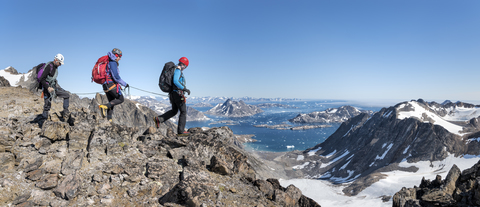 Grönland, Sermersooq, Kulusuk, Schweizerland Alpen, Bergsteiger beim Wandern in felsiger Berglandschaft, lizenzfreies Stockfoto