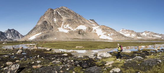 Greenland, Sermersooq, Kulusuk, Schweizerland Alps, woman walking at a brook - ALRF00954