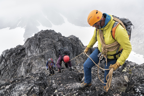 Greenland, Sermersooq, Kulusuk, Schweizerland Alps, mountaineers with rope ascending rocky mountain stock photo