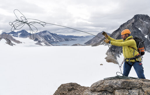 Grönland, Sermersooq, Kulusuk, Schweizerland Alpen, Bergsteiger auf dem Gipfel beim Seilwerfen - ALRF00995