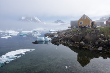 Grönland, Sermersooq, Kulusuk, Holzhütten am Ufer und auf dem Wasser treibendes Eis - ALRF00997