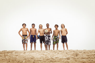 Porträt von Jungen, die auf Sand gegen einen klaren Himmel stehen - CAVF04085