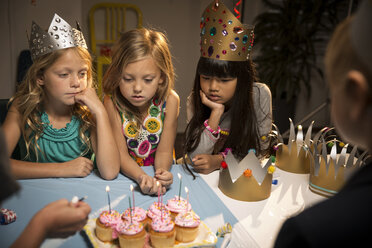 Hohe Winkelansicht von Kindern mit Blick auf Tassenkuchen auf dem Tisch - CAVF04100