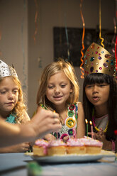 Lächelnde Freunde betrachten Tassenkuchen während einer Geburtstagsfeier - CAVF04101