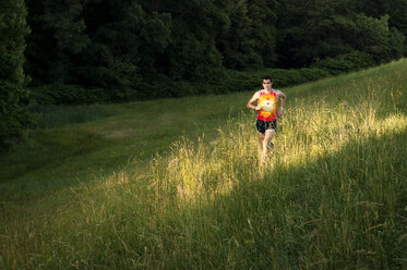 Mann joggt auf einem grasbewachsenen Feld - CAVF04119