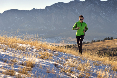 Mann joggt auf Feld gegen Berge, lizenzfreies Stockfoto