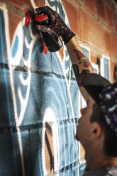 Mann sprüht Graffiti auf Ziegelmauer - CAVF04148