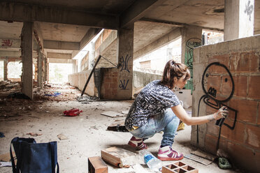 Frau sprüht Graffiti auf Hauswand - CAVF04150
