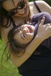 Fröhliche Mutter und Tochter umarmen sich im Park - CAVF04155