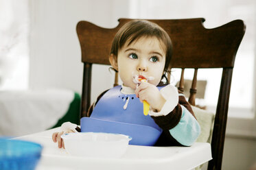 Baby boy looking away while eating at table in home - CAVF04206