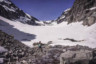 Rückansicht einer Frau beim Wandern auf einem schneebedeckten Berg - CAVF04384