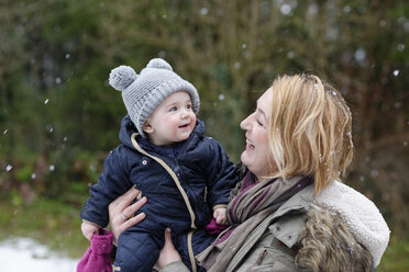 Baby girl on arms of her mother watching snowflakes for the first time - LBF01841