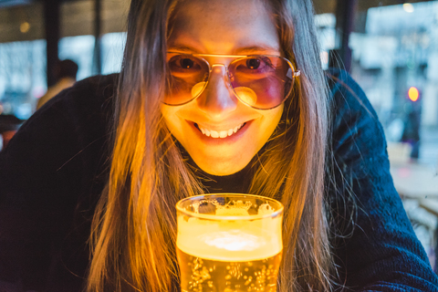 Paris, Frankreich, Porträt einer glücklichen jungen Frau mit einem Glas Bier in einer Kneipe am Abend, lizenzfreies Stockfoto