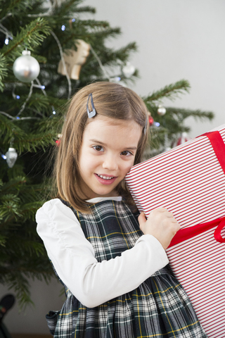 Porträt eines lächelnden kleinen Mädchens mit Weihnachtsgeschenk, lizenzfreies Stockfoto