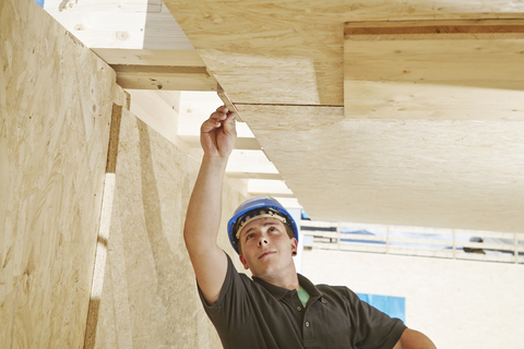 Österreich, Arbeiter kontrolliert Dachkonstruktion, lizenzfreies Stockfoto