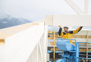 Austria, worker on hoist, positioning roof construction - CVF00276