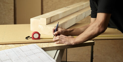 Worker marking wood with pencil, tape measure - CVF00283