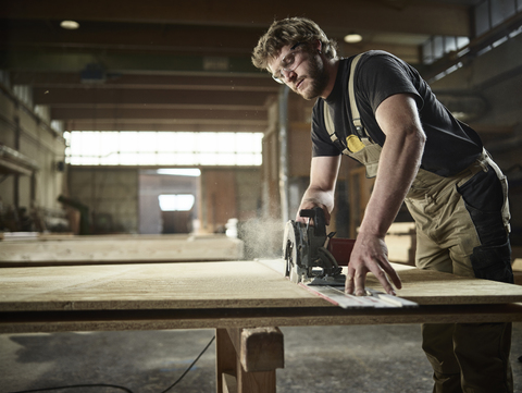 Zimmermann sägt Holz mit Handsäge, lizenzfreies Stockfoto