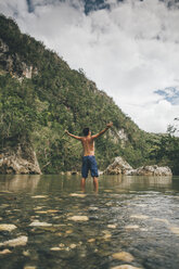 Kuba, Baracoa, Junger Mann steht im Yumuri-Fluss, Rückansicht - GUSF00560
