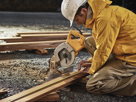 Man measuring decking board, circular saw stock photo